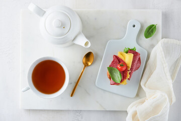 Salami sandwich. Delicious toasted sandwiches with slice salami, cheddar cheese lettuce and tomatoes cherry on white marble background. Restaurant menu, cafe, recipe or article concept. Mock up.