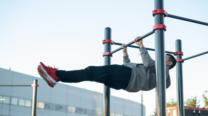Young caucasian man doing parallel bars exercise outdoors. 