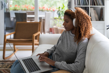 Attractive african american woman is using a computer and listening music