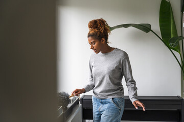 Joyful african american woman cleaning room with broom