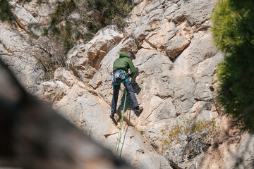 Male mountaineer climbing cliff in daytime
