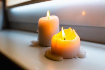 Two burning candles on windowsill.Two candles on a windowsill at home interior.Closeup.