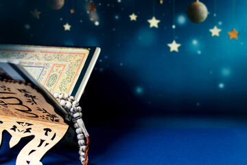 Holy Al Quran and tasbih or rosary beads on blue background.
