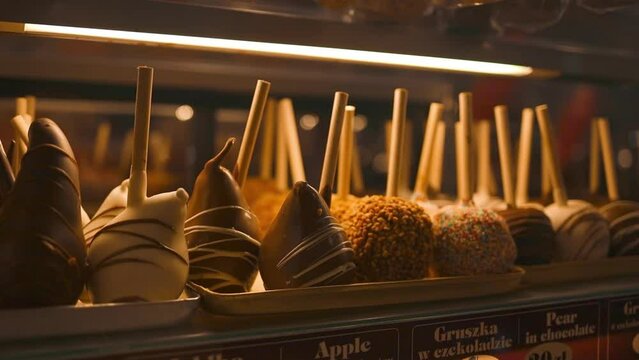 Delicious chocolate covered candy apples in a storefront window at Christmas market in Krakow. Pears covered with black, white and milk chocolate in a candy shop window. High quality FullHD footage