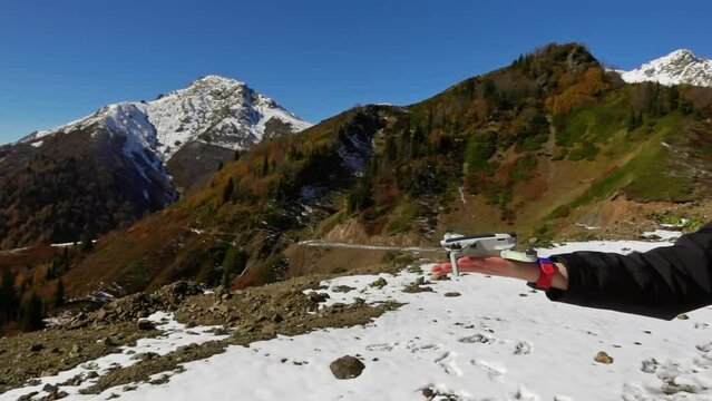 Man is piloting copter in the sky above mountains with snowy peaks filmed in closeup slow motion. Landscape of cliffs in Georgia and tourist filming scenery on drone. Travelling with modern devices