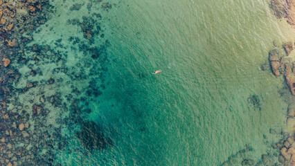 Aerial view from drone of people swimming in the middle of the sea of ​​turquoise green water, on a quiet Sydney beach in the reefs and corals