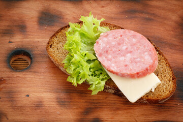 Cooked simple sandwich with smoked sausage, cheese and salad on cutting board - 692510990