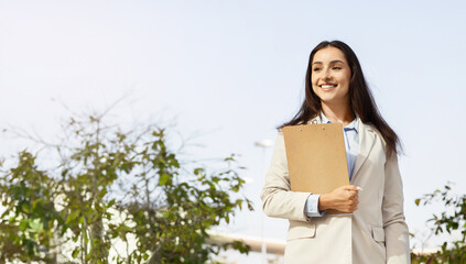 Obraz premium European happy young professional business woman hold clipboard outside in city