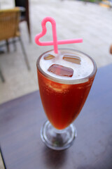 Close-up of the ice black tea with heart shape straw in outdoors. Food and drinks concept.