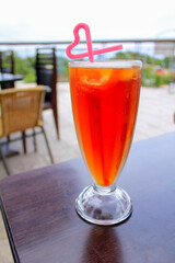 Close-up of the ice black tea with heart shape straw in outdoors. Food and drinks concept.