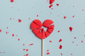 Valentine day concept with broken red lollipop heart on pastel blue background top view. Flat lay...