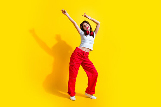 Full length photo of adorable positive lady wear white t-shirt earphones having disco fun isolated yellow color background