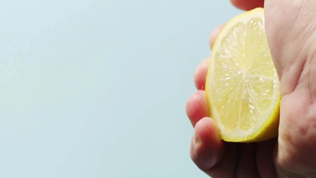 Closeup shot of person's hands squeezing lemon juice. Human squeezes half of lemon.