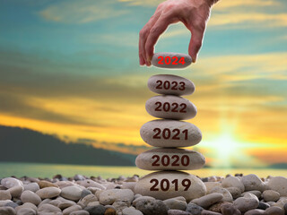 The concept of new year savings. The man leaves a year stone on the blocks. Anniversary 2024 is the...