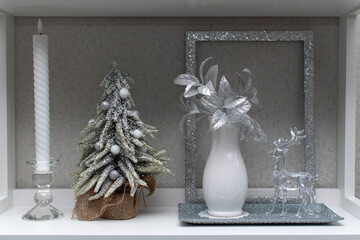 Still life with a candle, christmas tree, vase with flowers and glass deer	
