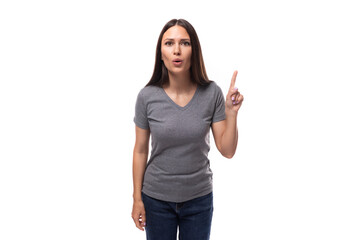 young well-groomed caucasian woman with dark straight hair is dressed in a casual gray t-shirt on a studio background with copy space