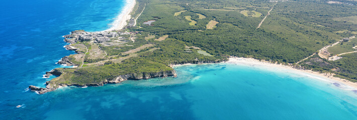 Macao beach with sandy coastline, turquoise water and stone cliff. Famous seashore for surfing in Dominican Republic. Aerial drone view . Long banner