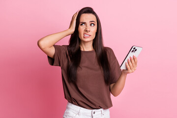 Portrait of young unsatisfied lady grin teeth using smartphone touch head look empty space oops failed isolated on pink color background