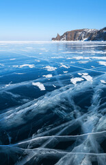 Winter wonderland of icy travel on frozen Baikal Lake. Scenic landscape with transparent blue ice...