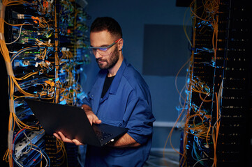 Repairman is busy and working with internet equipment and wires in server room