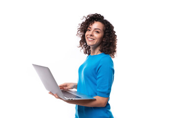 a young woman with a curly hairstyle dressed in a blue T-shirt works at a laptop