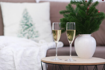 Two glasses of Champagne on caffee table in living room. Christmas home interior. Ceramic vase with...