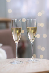 Two glasses of Champagne on light background on caffee table in living room. Christmas home interior.