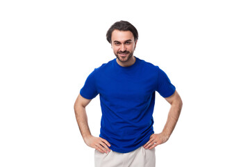 young well-groomed brunette man with a beard dressed in a blue T-shirt among a white background