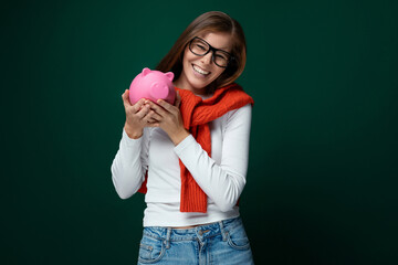 Smart young woman with brown hair keeps her money in a piggy bank