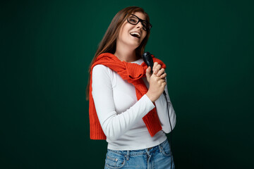 Charming young woman with a microphone sings a karaoke song