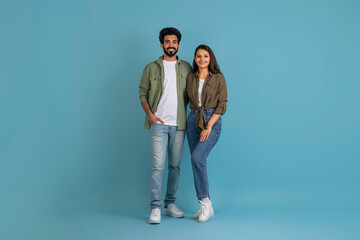 Happy young indian couple posing on blue, holding hands