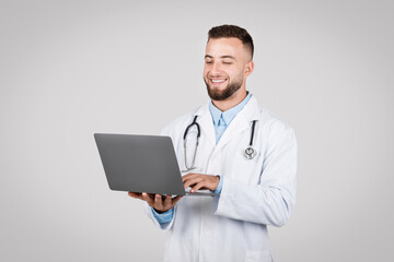 Smiling doctor using a laptop, technology in healthcare
