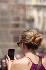 female tourist taking photo of astronomical clock with mobile phone in Prague