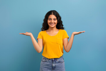Positive young curly hindu woman holding something invisible