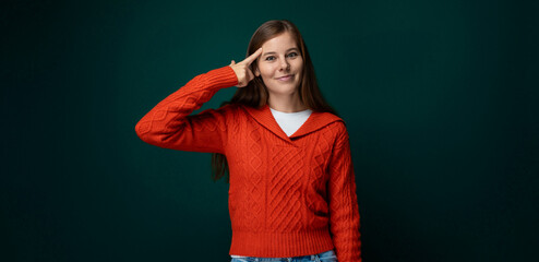 Attractive young woman dressed in a red sweater smiling on a green background