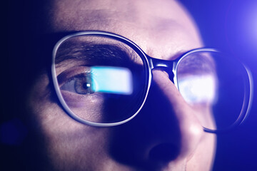 Man works on internet. Reflection at the glasses from laptop..Close up of man's eyes with black female glasses for working at a computer. Eye protection from blue light and rays.
