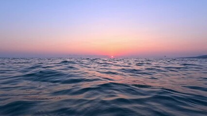 View from the surface of the sea at sunset. Chilling on the sea waves and watching the setting sun go below the horizon