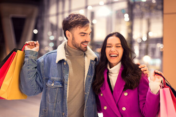 cheerful European couple enjoys winter shopping laughing during walk outside