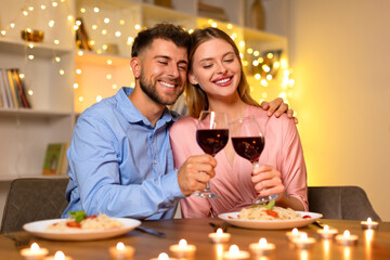Cuddling couple toasting wine glasses in a romantic setting