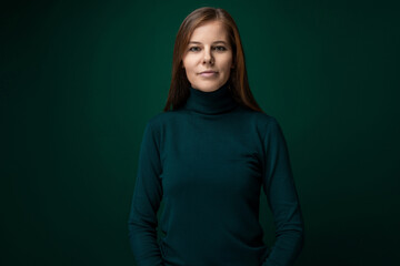 Fototapeta premium Portrait of a well-groomed young woman with brown eyes on a dark green background