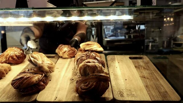 Stockholm, Sweden A server in a cafe fills a display case with sweet buns like cinnamon rolls and croissants. 