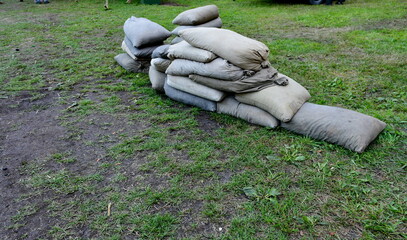 A close up on a machine gun replica from World War I seen next to some sandbags and ammo crates spotted next to a camp seen on a cloudy summer day during a historic reenactment in Poland