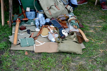 A view of a military themed camp with numerous weapons, suits, uniforms, metal equipment, bags, pouches and other utensils presented for display seen on a sunny summer day in Poland