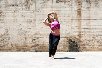 Fit woman dancing on sidewalk on sunny day