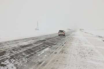 Snow drift over an asphalt road through a field