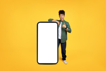Emotional guy posing by big smartphone with white blank screen