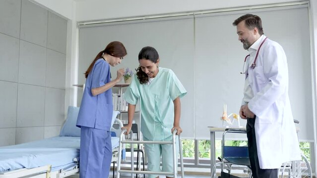 Nurse help women patient with walking aids after received a treatment, doctor standing observation clap hands cheer up, patient happy for cure and can walk again.
