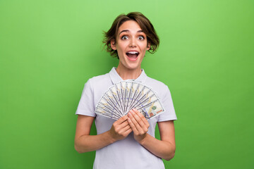 Photo of impressed funky girl dressed grey polo showing money fan isolated green color background