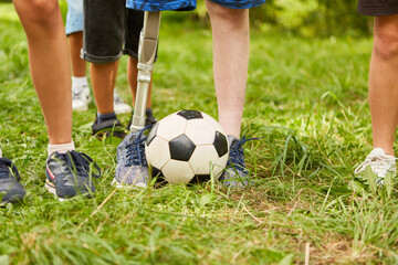 Boy with amputated leg playing soccer at park