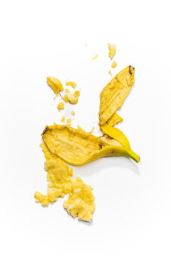 A smashed banana with peel against a white background